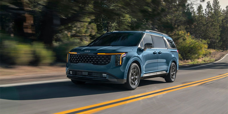 A 2025 Kia Carnival driving down a forest road near New Port Richey, FL 