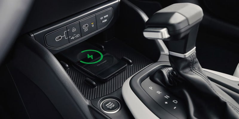 Kia K4 center console featuring a wireless smartphone charging pad, USB-C ports, vehicle controls